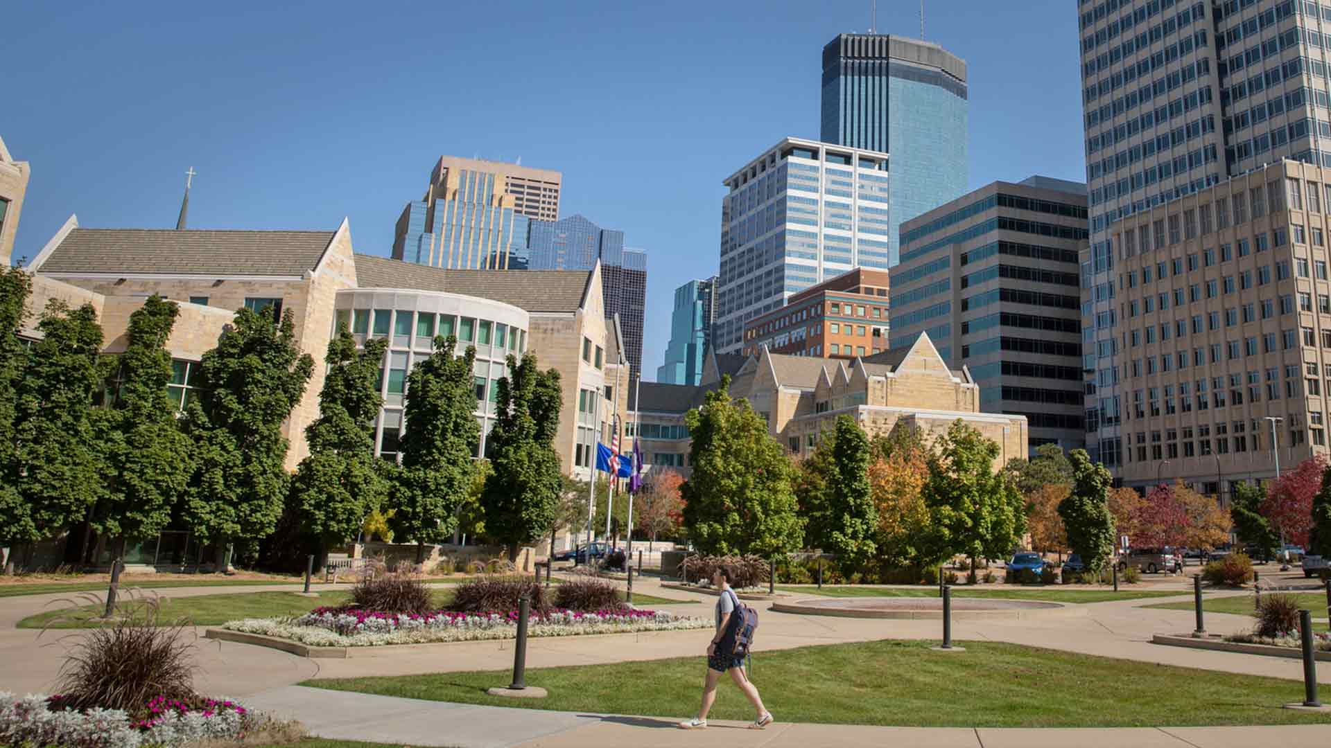 Student walking outside on campus with Minneapolis skyline in background