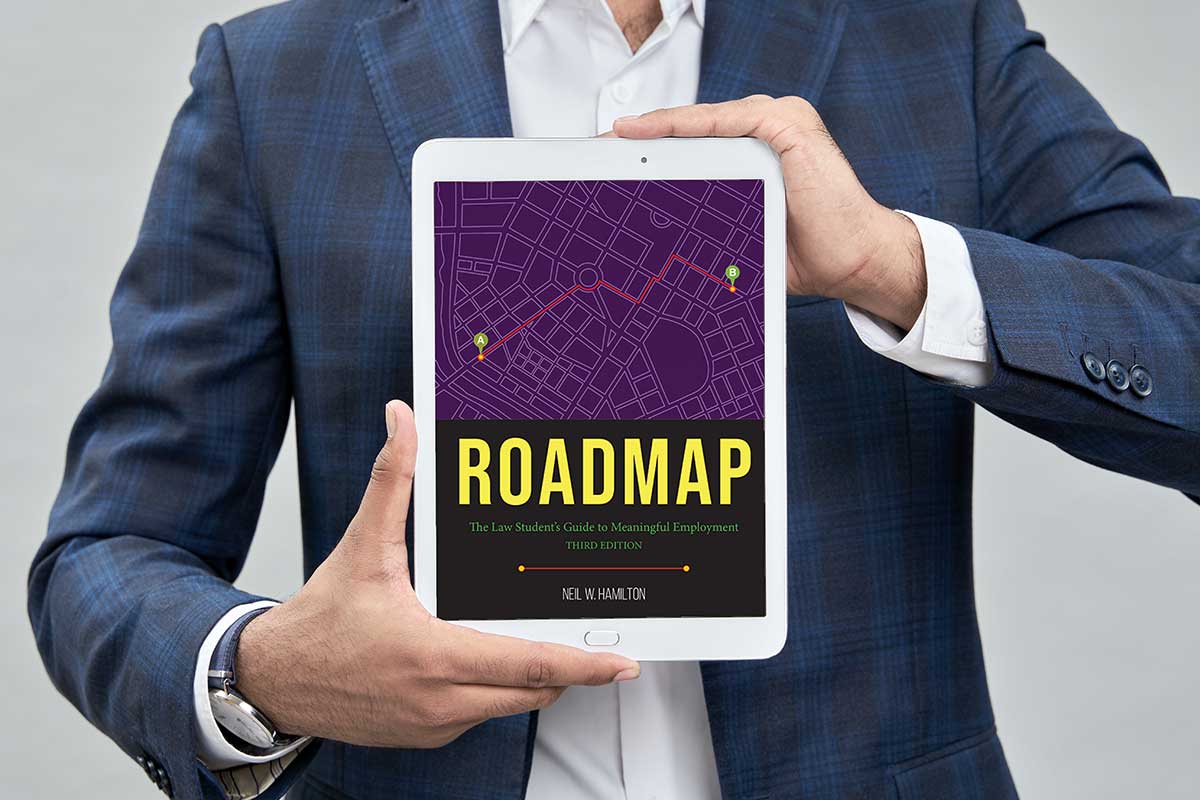 The book 'Roadmap for Employment' is held up on a tablet.
