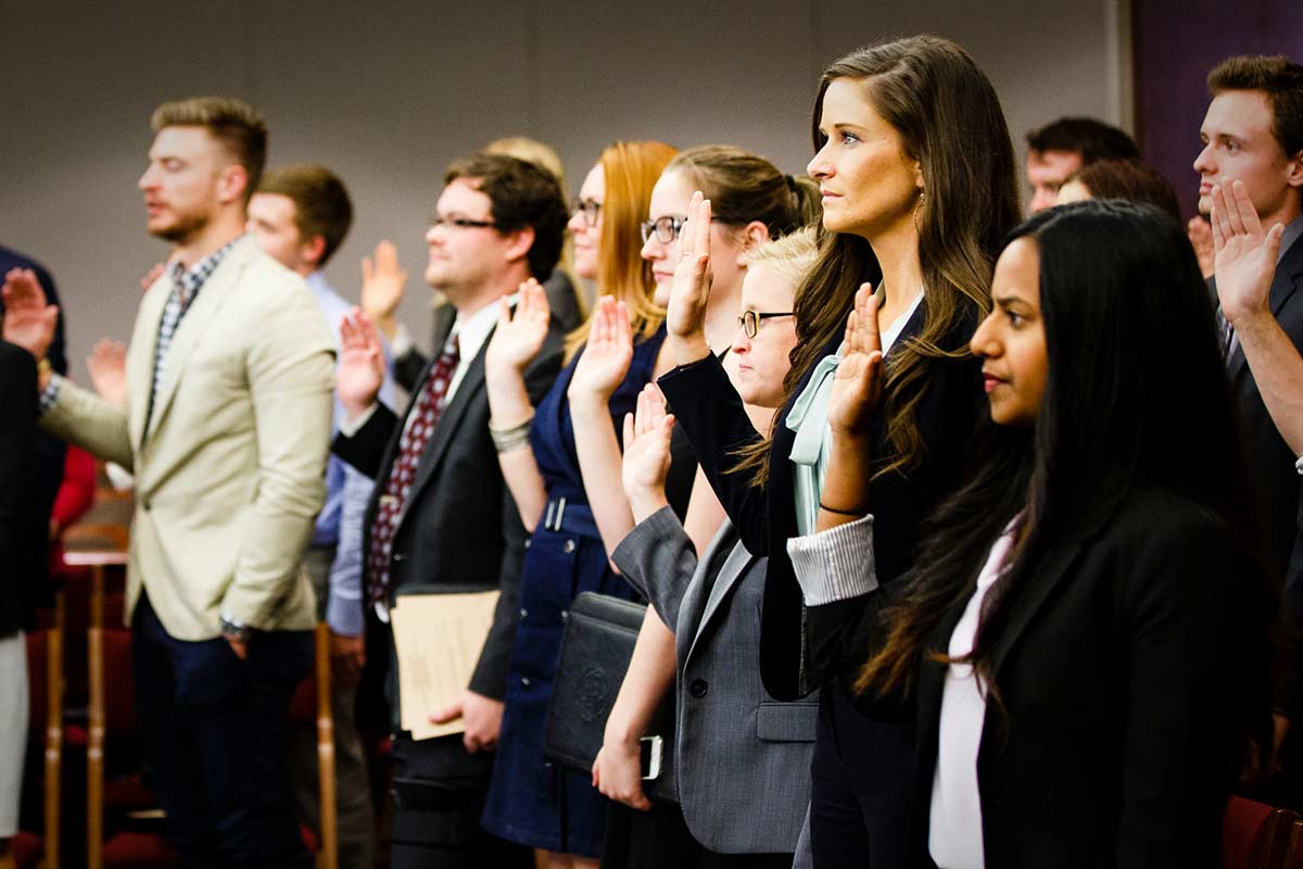 Law students raise their hands in oath.