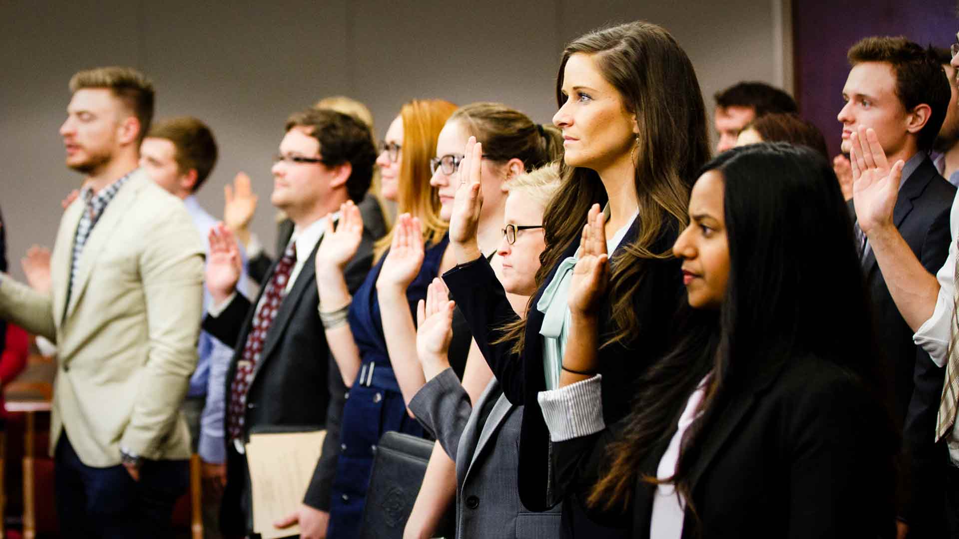 Law students raise their hands in taking an oath.