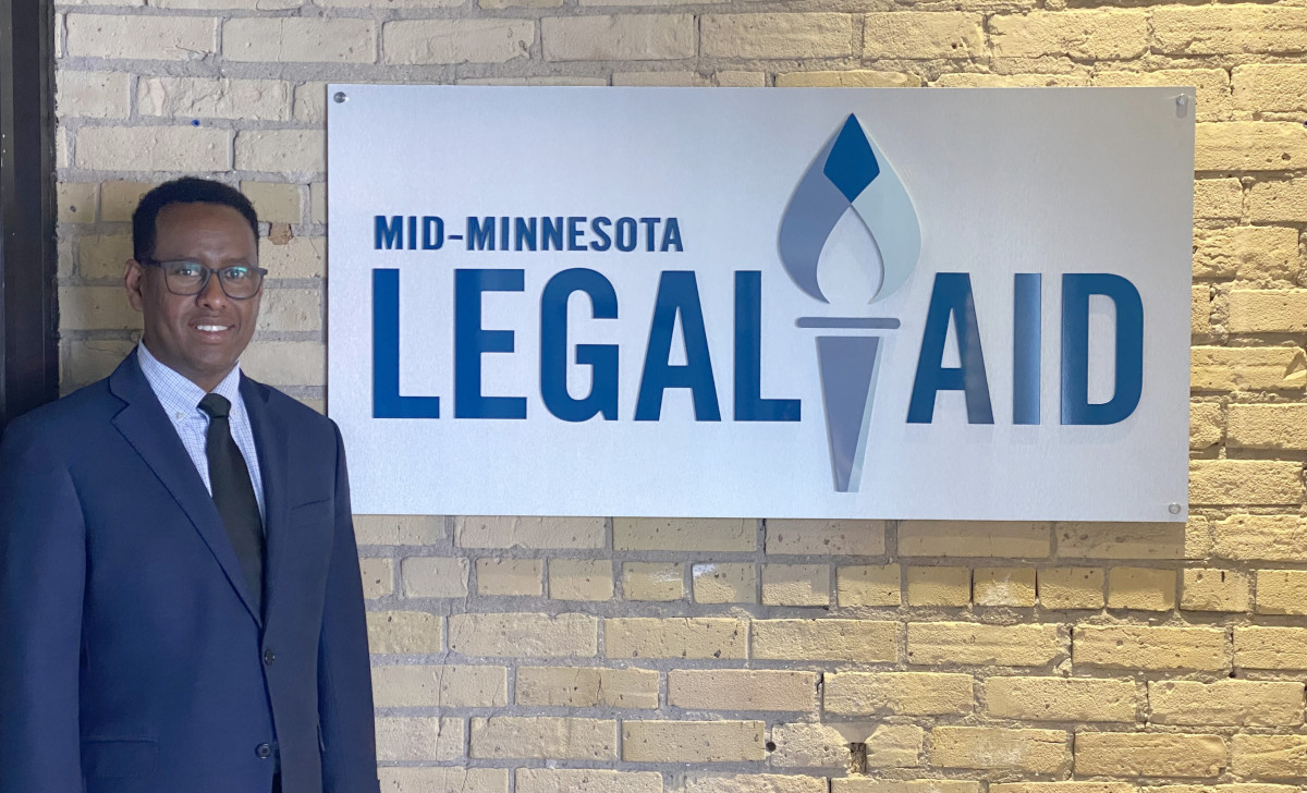 Extern standing in front of Mid-Minnesota Legal Aid sign