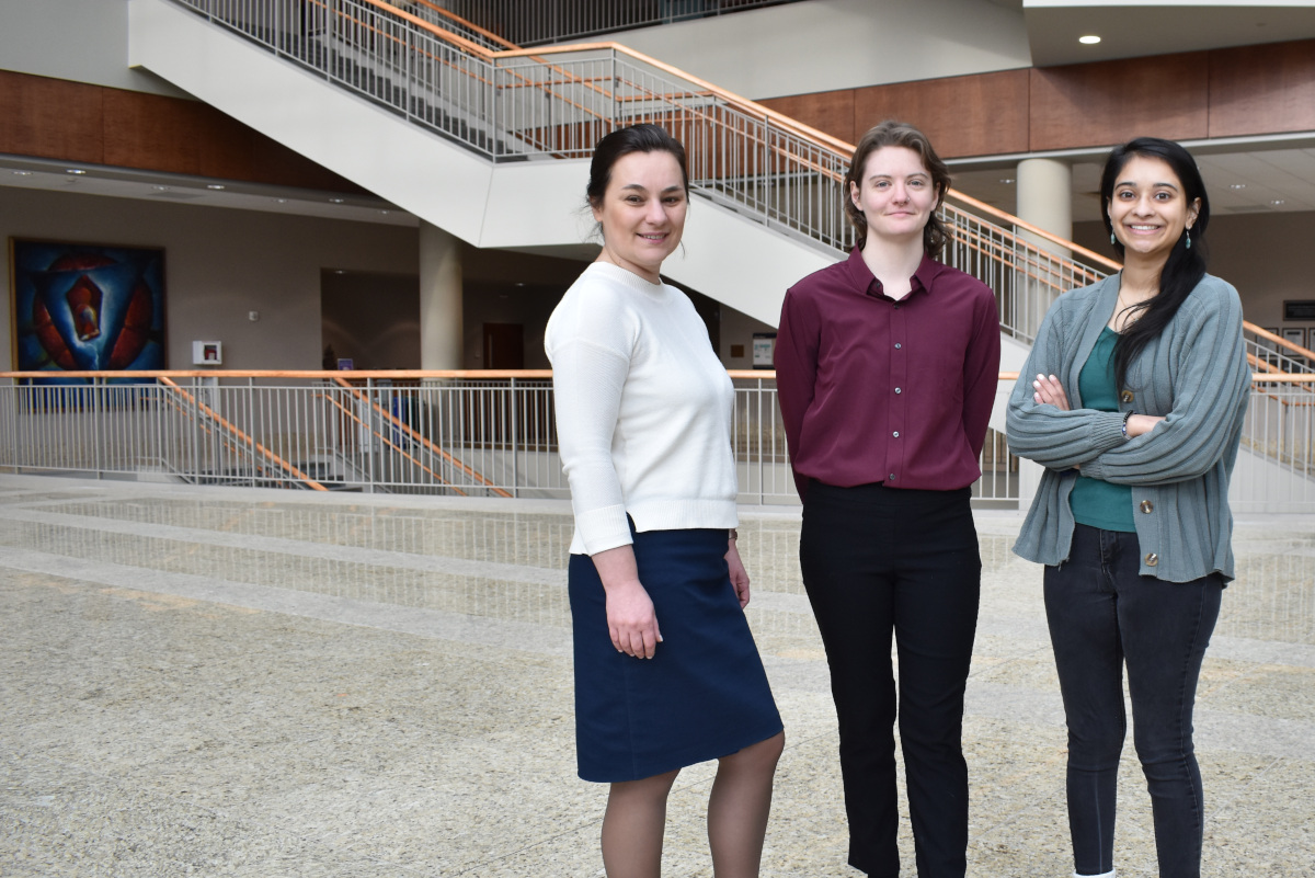 Three student practitioners in the immigration clinic pose in the law school's atrium