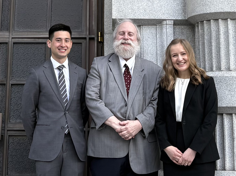 Two law students and their professor outside a court house